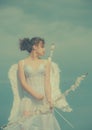 Angel girl in white angels dress with wings holding bow and arrow. Happy valentines day. Teen love and romance concept. Royalty Free Stock Photo