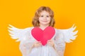 Angel with heart. Valentines day. Little cupid angel child with wings. Studio portrait of angelic kid. Royalty Free Stock Photo