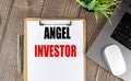 ANGEL INVESTOR text on clipboard paper with laptop, mouse and pen Royalty Free Stock Photo