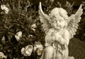 Angel made of clay sitting on a grave surrounded by flowers Royalty Free Stock Photo