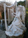 Garden ornament of angel playing a harp at side of pond Royalty Free Stock Photo