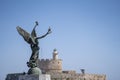 Angel Statue of Victory in Mandraki Harbour in in focus and in the background Saint Nicholas Fortress Royalty Free Stock Photo
