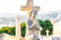 Angel statue with wings against tombstone cross in old cemetery. stone saint angel with praying hands at cemetery. Graveyard ancie Royalty Free Stock Photo