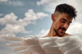 Young man with white wings and a blue sky with white clouds in the background Royalty Free Stock Photo