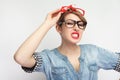 Anger sexual young woman in casual blue denim shirt with makeup standing, wearing lots of colorful spectacles at the same time, Royalty Free Stock Photo