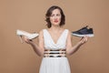 Anger woman in white dress holding high heels and sneakers and l