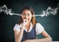 anger young woman with steam on ears and hand on the mouth. Black and grey background Royalty Free Stock Photo