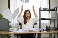 Angered, furious Asian businesswoman throwing up papers at her office desk Royalty Free Stock Photo