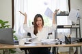Angered and mad Asian businesswoman screaming and throwing up papers at her desk Royalty Free Stock Photo