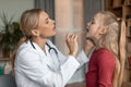 Angina, tonsillitis, cold and flu in children concept. Female doctor pediatrician checking patient little girl throat Royalty Free Stock Photo