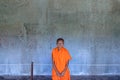 Angkor, Cambodia - december 10, 2018: young buddhist monk portrait in Angkor Wat, majestic temple basreliefs in the background