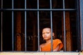 young novice buddhist monk peeking looking outside of the window from his monastery