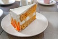 Angle closeup view of big slice of carrot cake on a white plate in a cafe Royalty Free Stock Photo