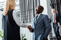 Angle view of blonde businesswoman shaking hands with african american businessman Royalty Free Stock Photo