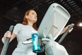 Angle view of focused overweight girl working out on stepper in gym