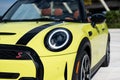 Angle view of front bumper and headlight of yellow luxury sporty convertible car with soft top down standing outside on