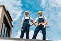 Angle view of handsome handymen standing with hands on hips