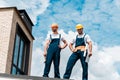 Angle view of handsome repairmen standing with hands on hips