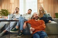 Angle view of a happy group of friends sitting on the sofa in the living room and watching a football match Royalty Free Stock Photo