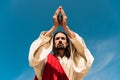 Angle view of jesus with praying hands against blue sky