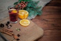 Angle view mulled wine with citrus, cinnamon, cardamon and anise spices and fir. Christmas cozy still life on wooden