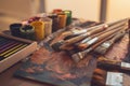 Angle view photo of palette with mixed oil paints, gouache, crayons and paintbrushes set in art studio. Royalty Free Stock Photo