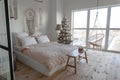 Angle view on spacious white bedroom with big windows decorated with Christmas New year tree and tea