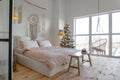 Angle view on spacious white bedroom with big windows decorated with Christmas New year tree and tea set