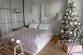 Angle view on spacious white bedroom decorated with Christmas New year tree and tea set