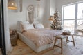 Angle view on spacious white bedroom decorated with Christmas New year tree and tea set standing on a bench