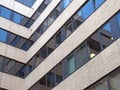 Angled corner of a large concrete office building with other modern buildings and blue sky reflected in rows of windows Royalty Free Stock Photo