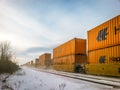 Angled photo of orange rail cars moving on track on a bright wintery day in Ontario, Canada.