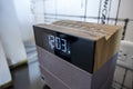 Angled view of a digital alarm clock on a bedside table in the bright, sunny afternoon