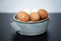 Angled view of handmade ceramic bowl of fresh organic brown and white eggs on dark and concrete background. Royalty Free Stock Photo