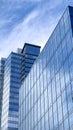 Angled view of a large, window covered building corner against a blue, cloud filled sky