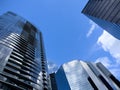 Angled view of large, window covered building corners against a blue, cloud filled sky