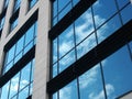 View of a modern commercial building with large mirrored windows reflecting blue sky and white clouds Royalty Free Stock Photo