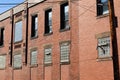 Angled view of old red brick industrial building, lower windows filled with glass block, interesting architectural details Royalty Free Stock Photo