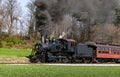 Angled View of a Restored Steam Passenger Train Moving Slowly Blowing Lots of Black Smoke