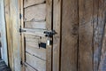 Angled view of a rustic, wooden door with a metal latch and padlock keeping it secure Royalty Free Stock Photo