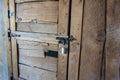 Angled view of a rustic, wooden door with a metal latch and padlock keeping it secure Royalty Free Stock Photo