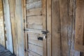 Angled view of a rustic, wooden door with a metal latch and padlock keeping it secure Royalty Free Stock Photo