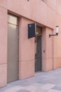 Angled View of Terracotta Wall with Metal and Glass Doors: Navigational Sign and Street Light Included