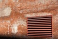 Angled view of weathered brick wall of an old industrial building with large HVAC exhaust vent painted red Royalty Free Stock Photo