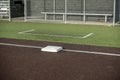 Angled view of a white base on a baseball field, with the view of a dugout in the background Royalty Free Stock Photo