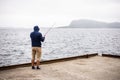 Angler catching the fish during dull rainy stormy wheather. Mountains at background