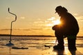 The angler fisherman at ice winter fishing. Sunset