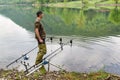 Fishing adventures, carp fishing. Fisherman with green rubber thigh high boots for fishing and camouflage shirt