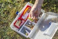 An angler`s rod chooses a spinning bait from the box.