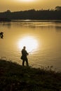 Anglers in romantic mood on the banks of a river at sunset Royalty Free Stock Photo